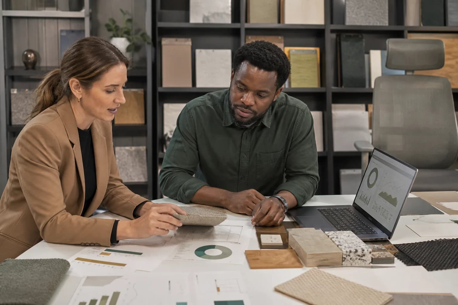 Architect and procurement manager reviewing office furniture materials and documentation