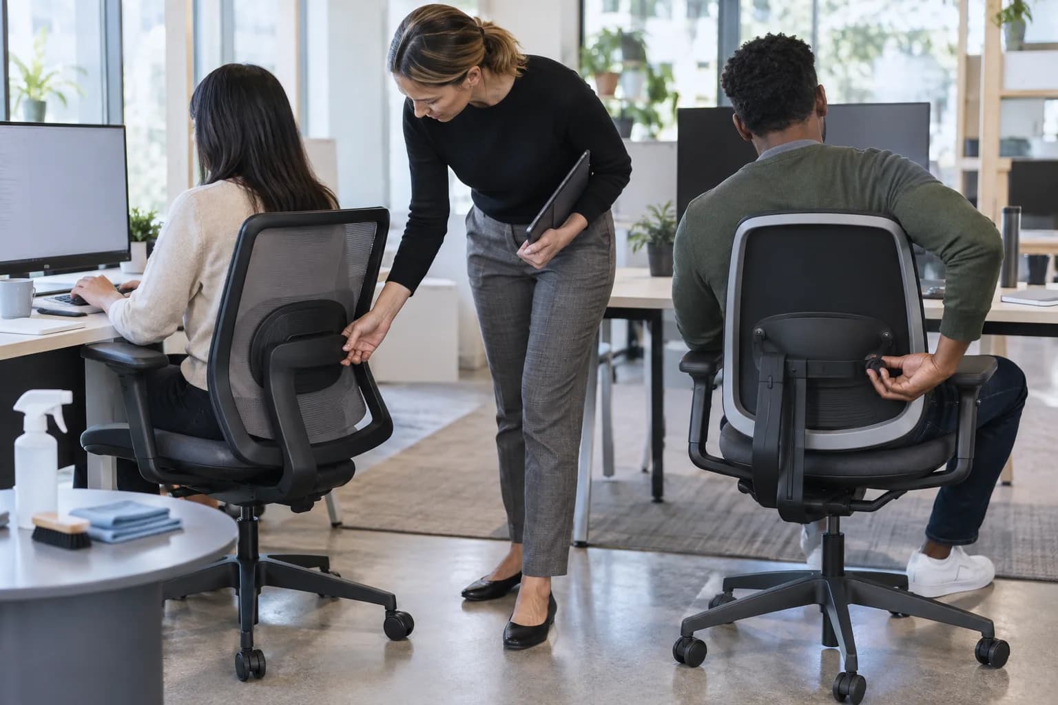 Representative users and a facilities buyer evaluating two unbranded chair lumbar systems at shared workstations