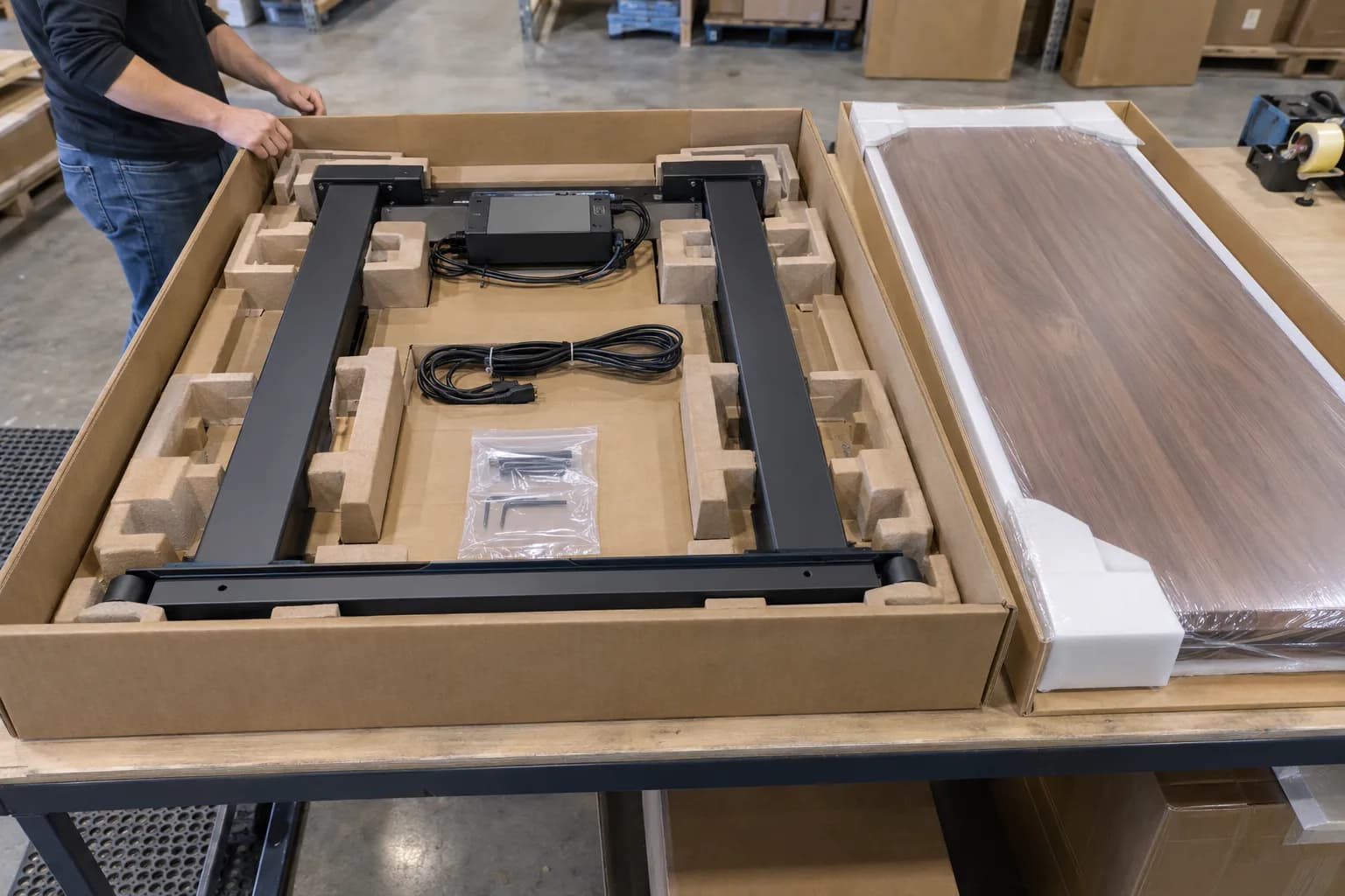 Unbranded standing desk columns, controller, cables and hardware immobilized in protective packaging before carton closure